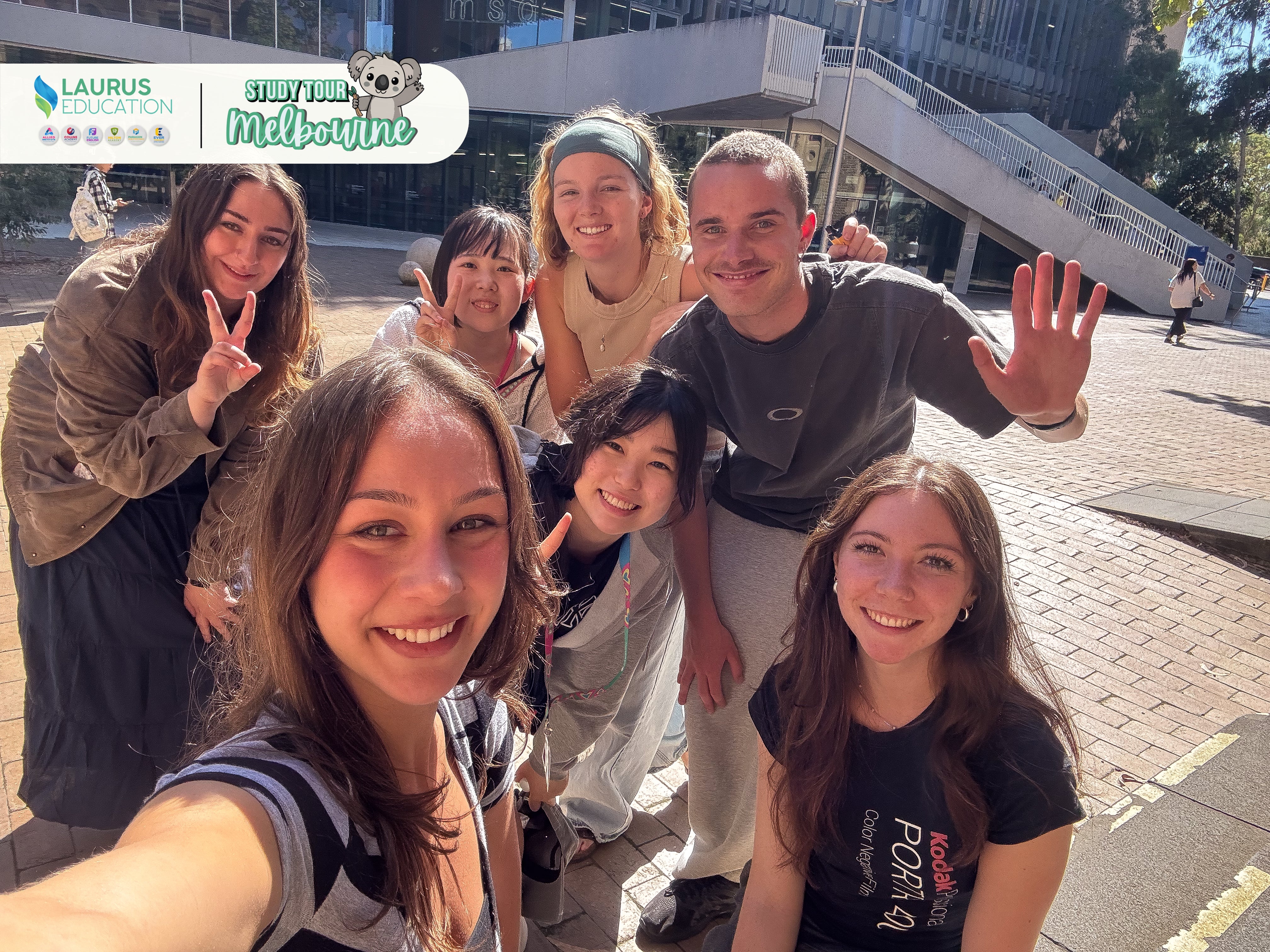 Group of people taking a selfie outdoors with 'Laurus Education' and 'St Kilda Melbourne' logos in the background.