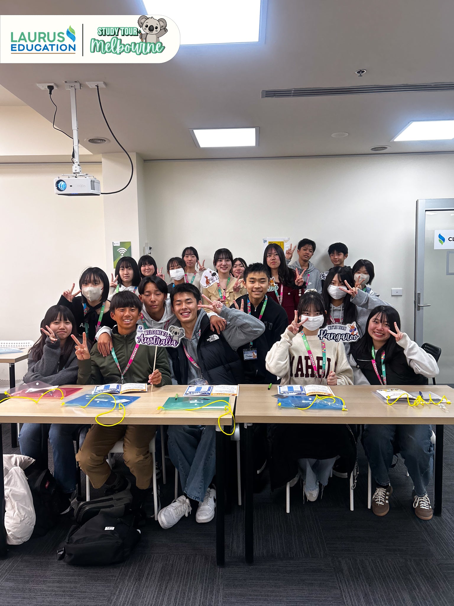 Group of students posing for a photo in a classroom setting with educational materials on the table.