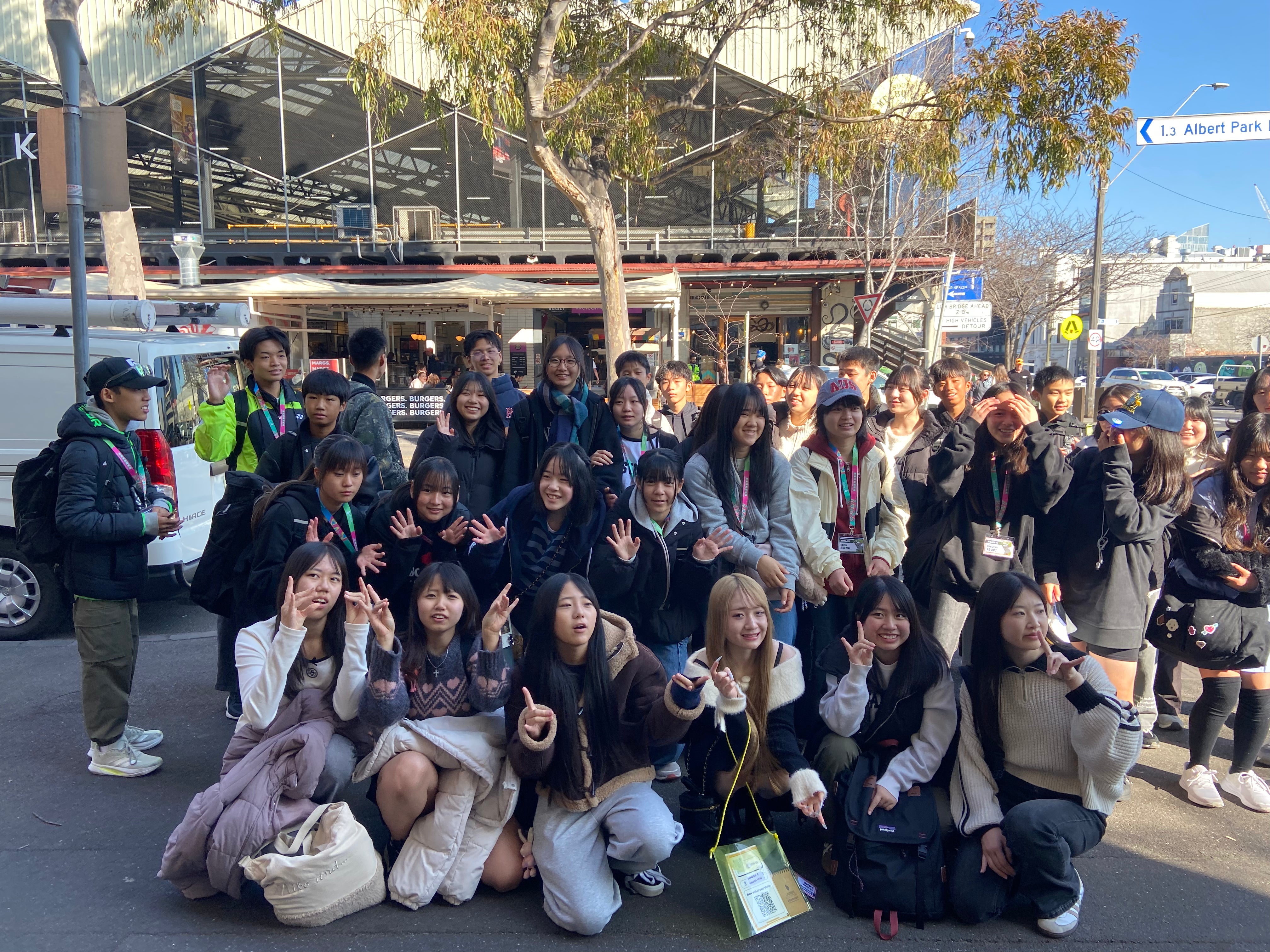 Group of people posing for a photo on a street with a building in the background